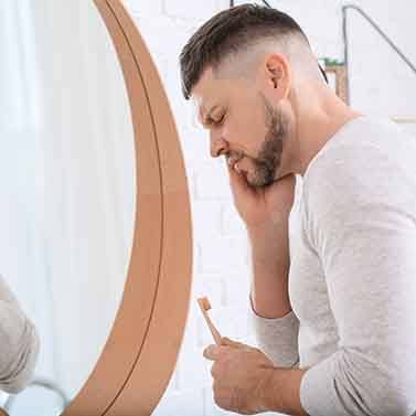 a man brushing his teeth and experiencing pain