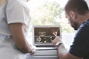 a dentist looking at X-rays on a monitor