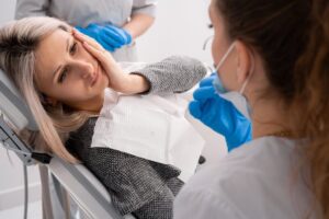 Woman with dental pain looked over at her dentist